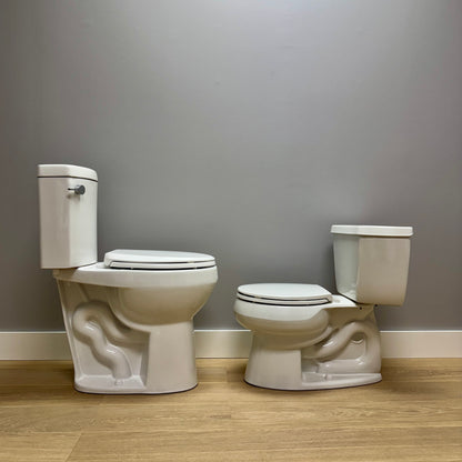 Two white toilets side by side against a gray wall.