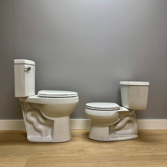 Two white toilets side by side against a gray wall.